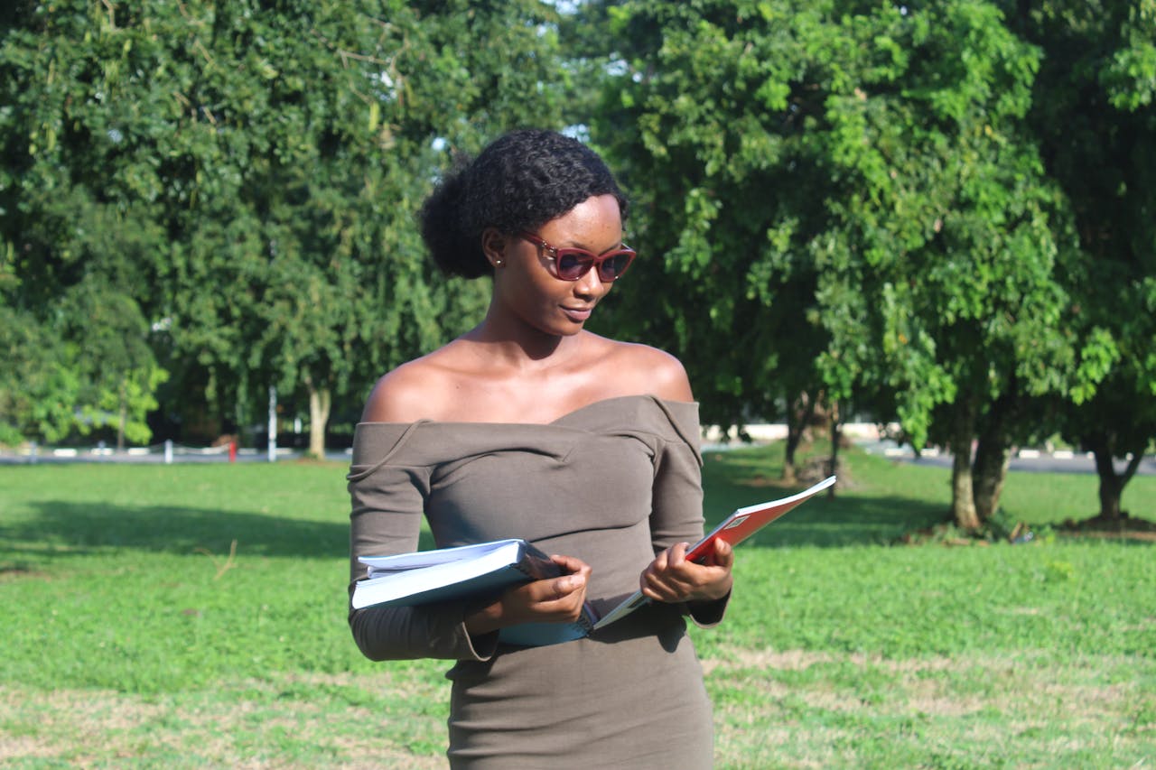 team-01 Young woman reading outdoors in Kumasi, Ghana. A sunny day for focused learning.